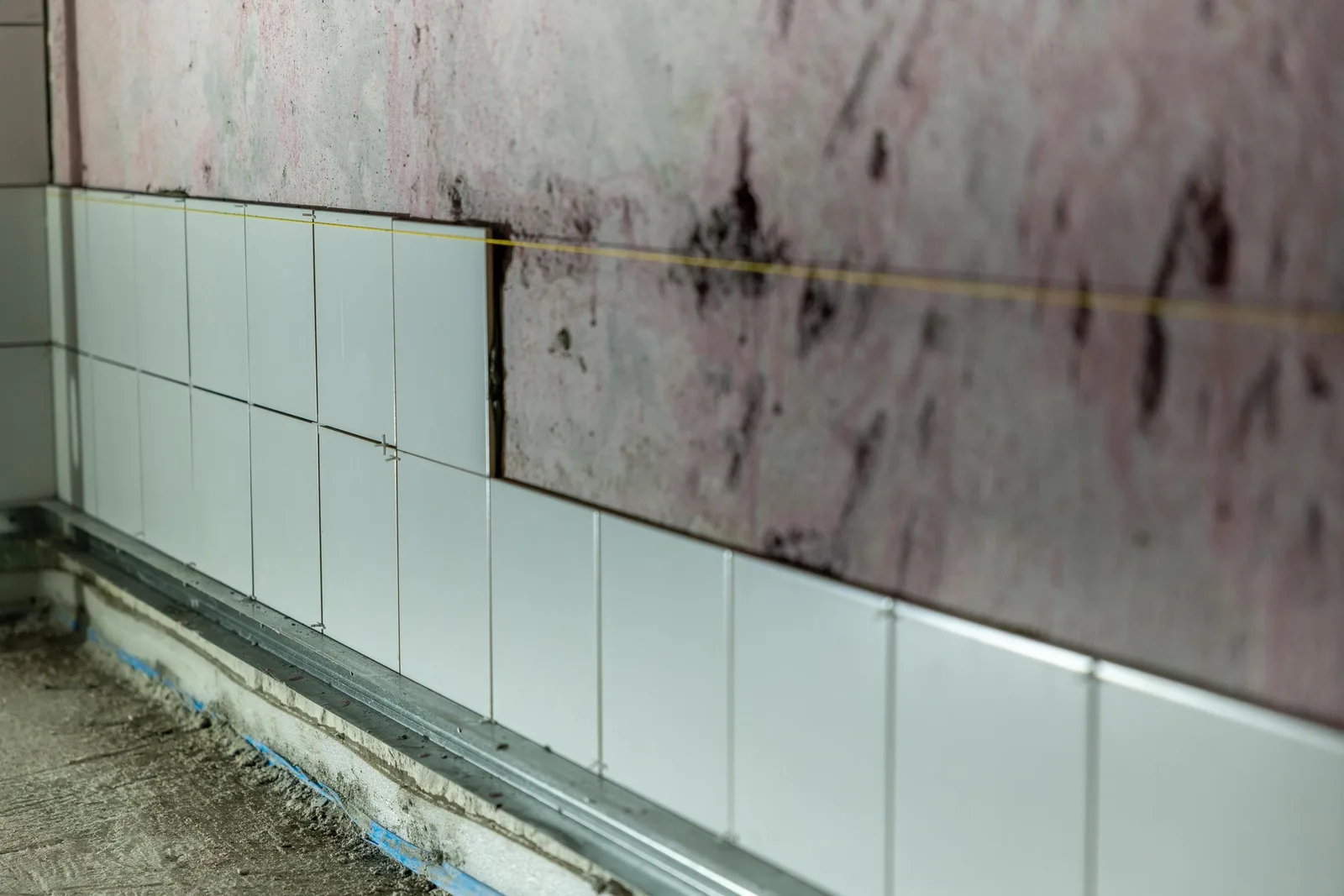 Azulejos recién colocados con crucetas de obra sobre una pared a medio alicatar